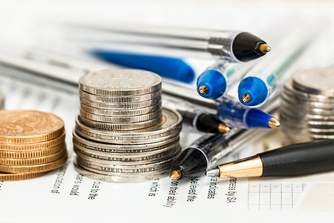 coin bills and pens on top of a report paper